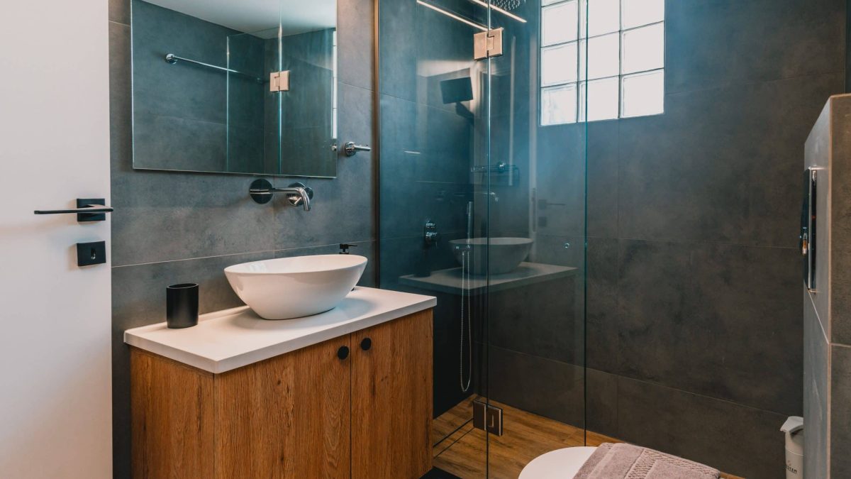 Luxury bathroom with walk-in shower and washing machine for guest use. Charys Premium Home.